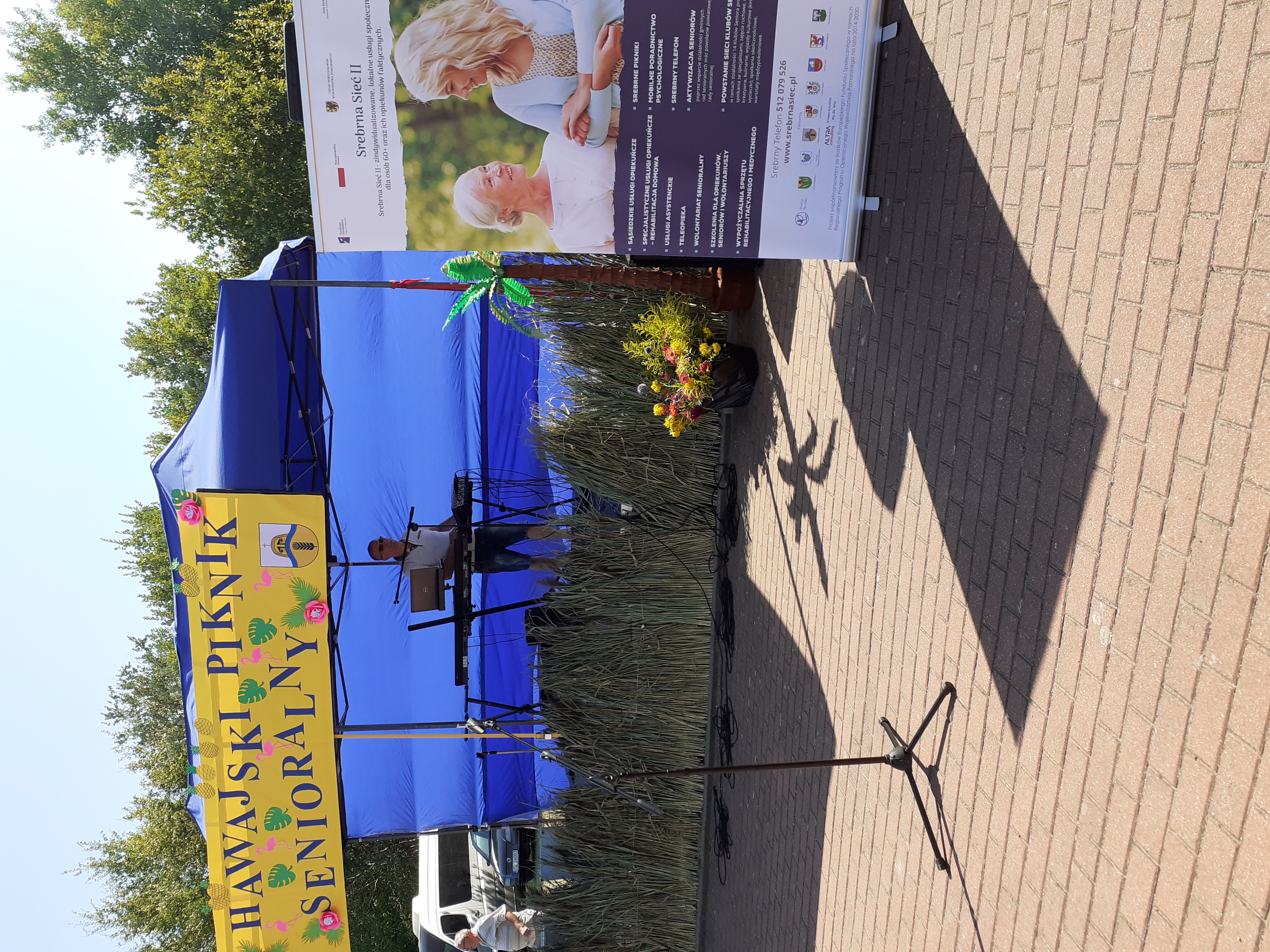 Scena dla muzyków z zawieszonym napisem - Hawajski Piknik Senioralny